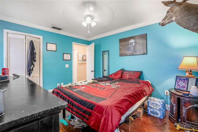 bedroom with ceiling fan, wood-type flooring, ornamental molding, and a closet