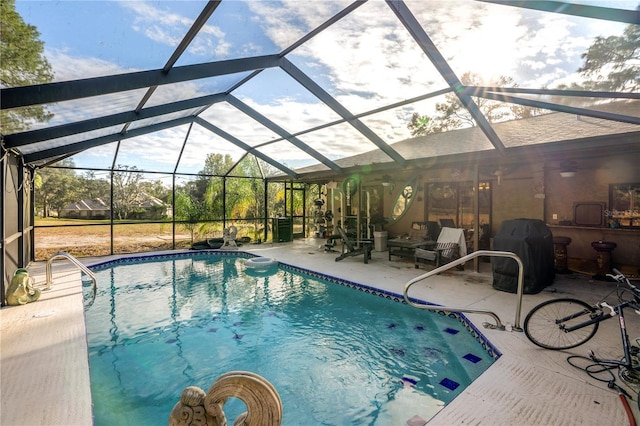 view of pool with glass enclosure, a grill, and a patio