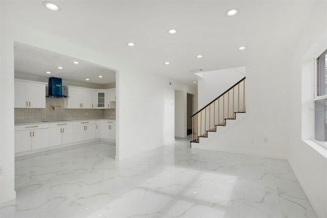 kitchen with white cabinets, wall chimney exhaust hood, and tasteful backsplash