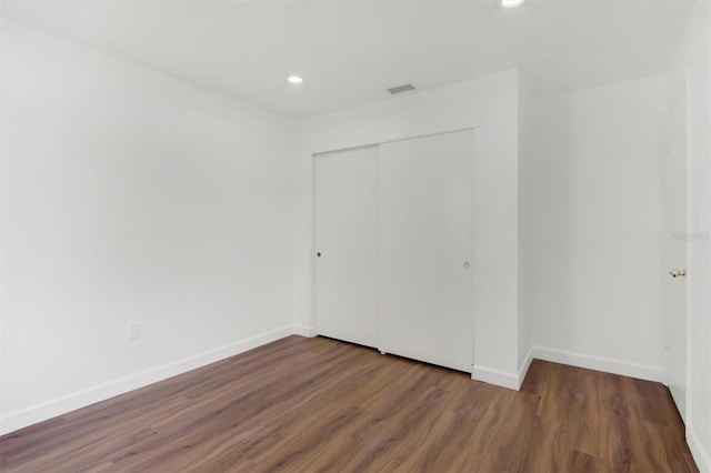 unfurnished bedroom with dark hardwood / wood-style flooring and a closet