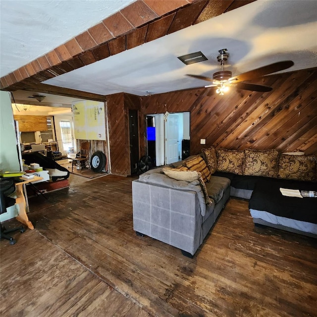 living room with dark hardwood / wood-style flooring, ceiling fan, and wooden walls