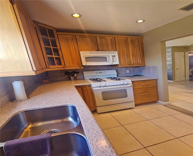 kitchen with light tile patterned floors, white appliances, and sink