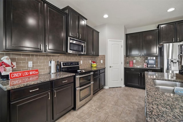 kitchen featuring sink, dark stone countertops, light tile patterned floors, appliances with stainless steel finishes, and tasteful backsplash