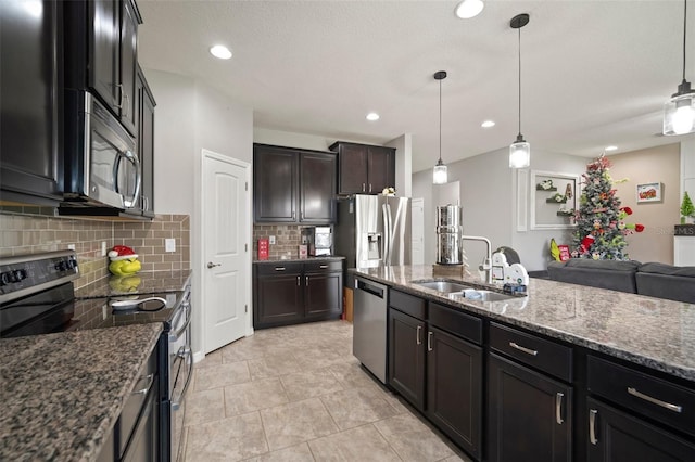 kitchen with dark stone counters, sink, stainless steel appliances, and decorative light fixtures