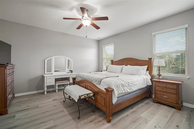 bedroom with ceiling fan, light wood-type flooring, and multiple windows