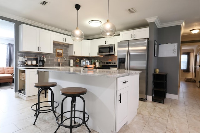 kitchen featuring white cabinets, appliances with stainless steel finishes, a center island, and a healthy amount of sunlight