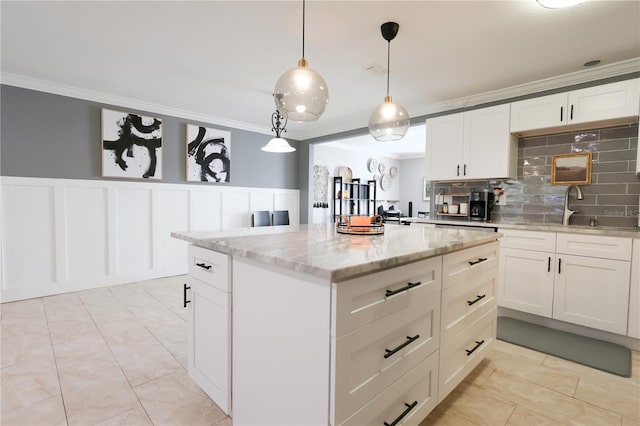 kitchen featuring light stone countertops, white cabinetry, backsplash, and hanging light fixtures