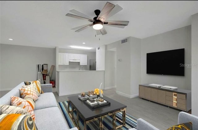 living room featuring light hardwood / wood-style flooring and ceiling fan