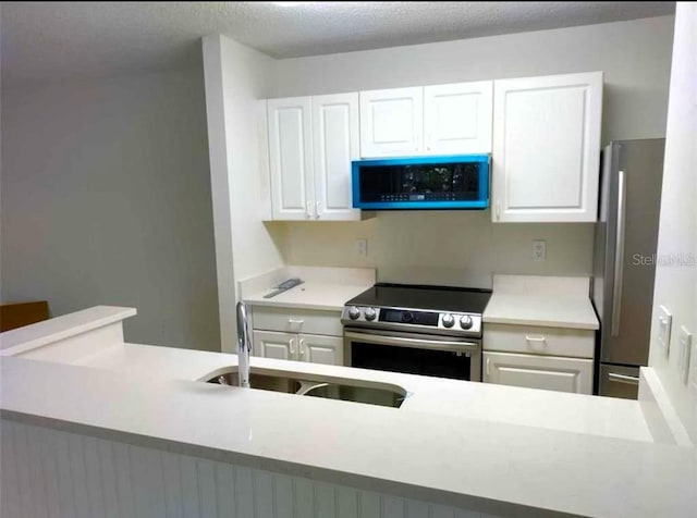 kitchen featuring sink, white cabinets, stainless steel appliances, and a textured ceiling