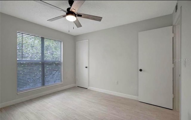 spare room featuring ceiling fan, light hardwood / wood-style floors, and a textured ceiling