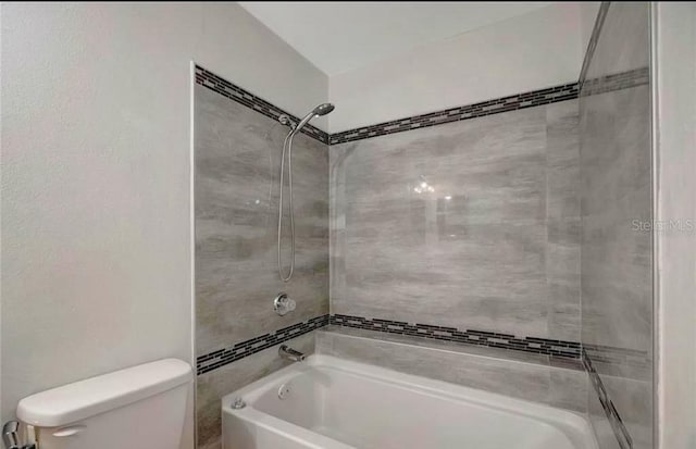 bathroom featuring toilet and tiled shower / bath