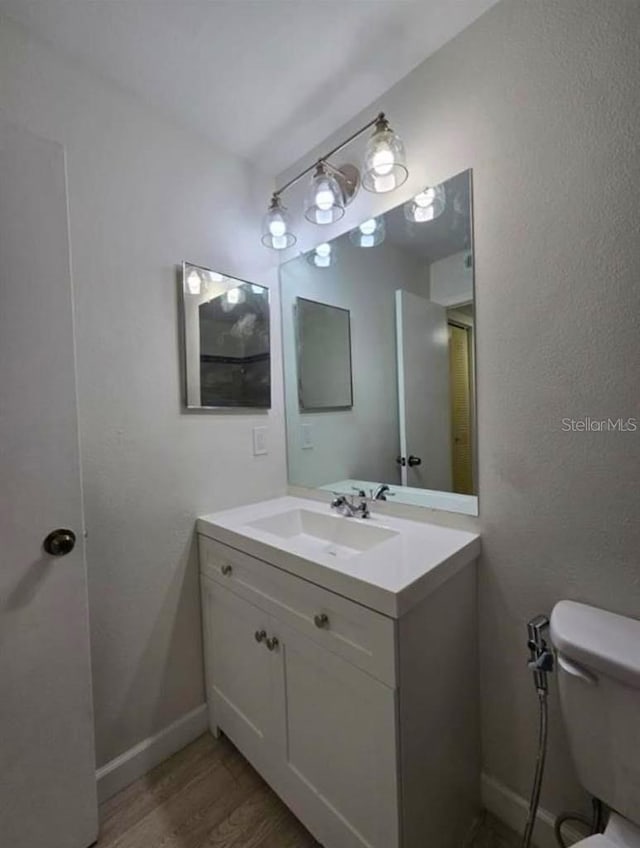 bathroom with vanity, wood-type flooring, and toilet