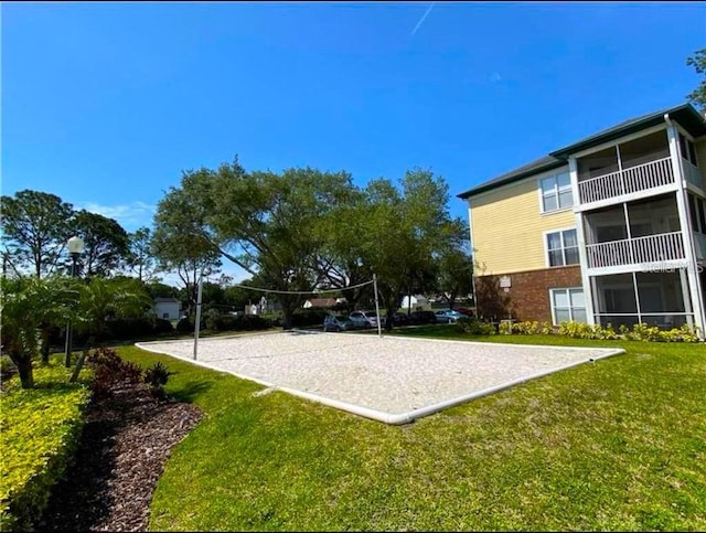 view of community with volleyball court and a lawn