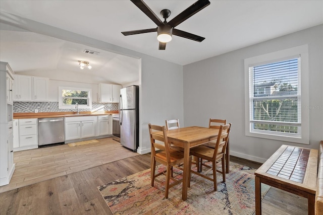 dining space featuring a wealth of natural light, light hardwood / wood-style flooring, ceiling fan, and sink