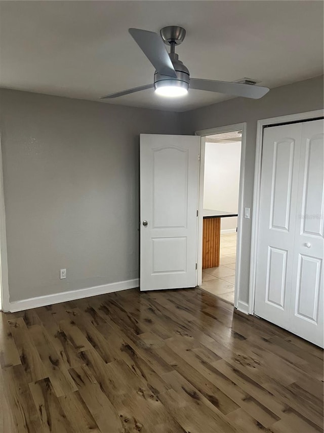 unfurnished bedroom featuring ceiling fan, dark hardwood / wood-style floors, and a closet