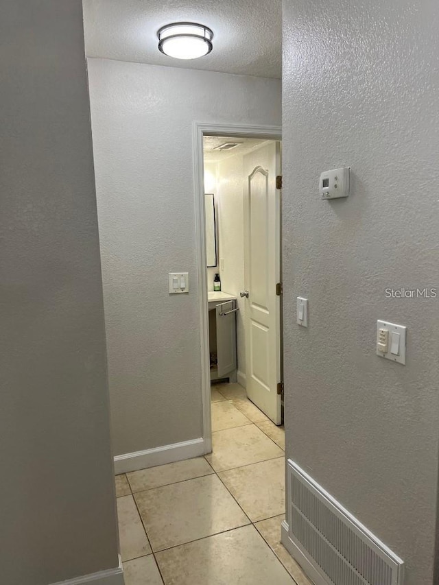 corridor with a textured ceiling and light tile patterned floors