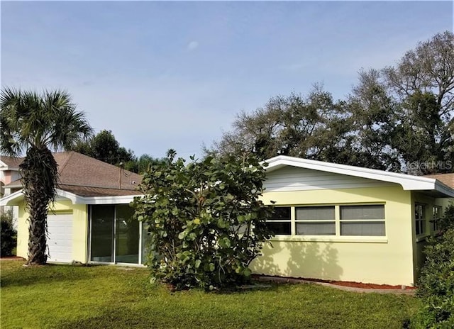 back of property featuring a garage and a yard