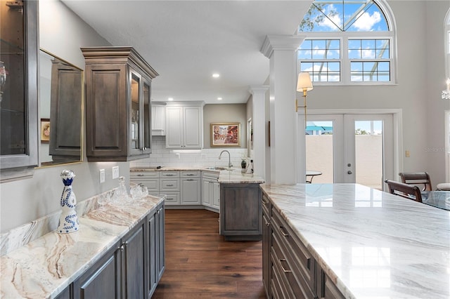 kitchen featuring dark brown cabinetry, sink, backsplash, and dark wood-type flooring