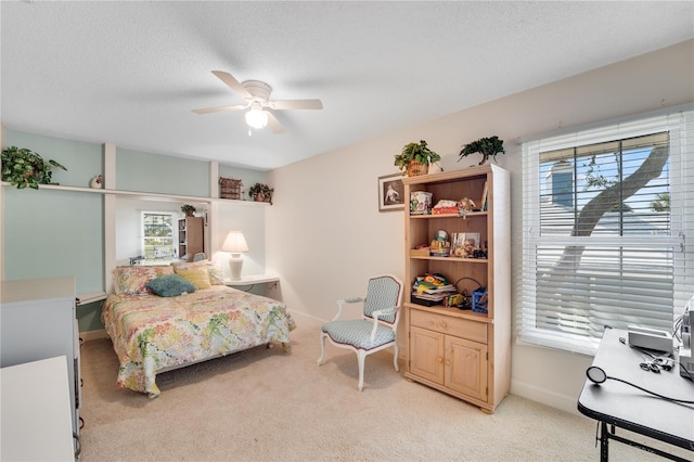 bedroom with ceiling fan, light colored carpet, and a textured ceiling