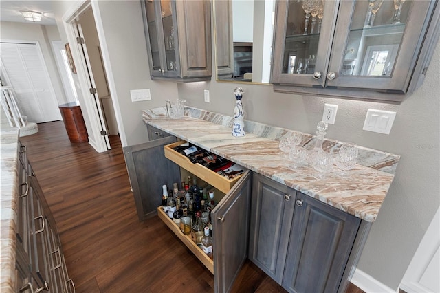 bar with light stone countertops and dark hardwood / wood-style flooring