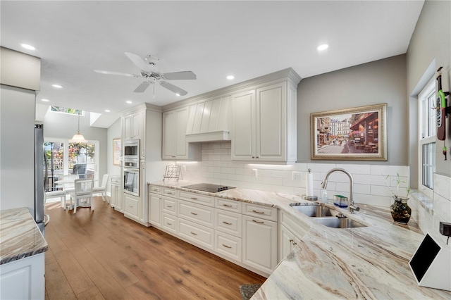 kitchen featuring sink, light stone counters, hanging light fixtures, appliances with stainless steel finishes, and white cabinets