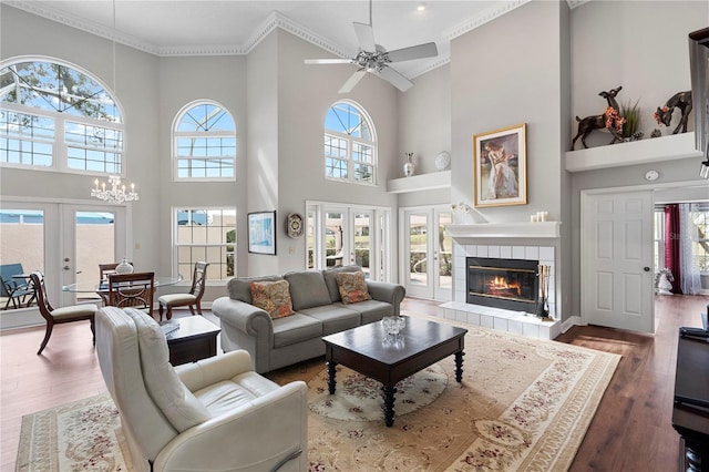 living room with a tile fireplace, wood-type flooring, crown molding, and french doors