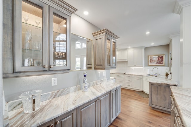 kitchen with light stone countertops, sink, backsplash, and light hardwood / wood-style floors