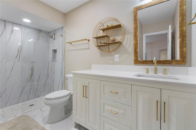 bathroom with vanity, toilet, and a tile shower