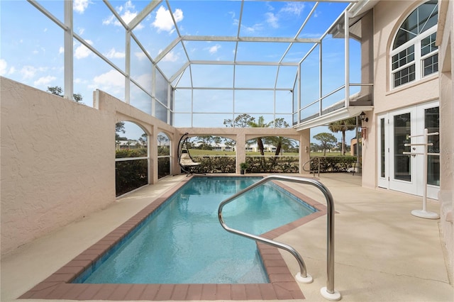 view of swimming pool featuring a patio area, glass enclosure, and french doors