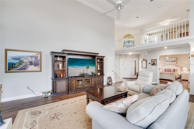 living room with hardwood / wood-style flooring, ceiling fan, and a high ceiling