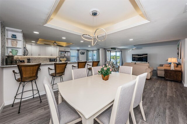 dining space featuring a tray ceiling, dark hardwood / wood-style floors, and ceiling fan with notable chandelier