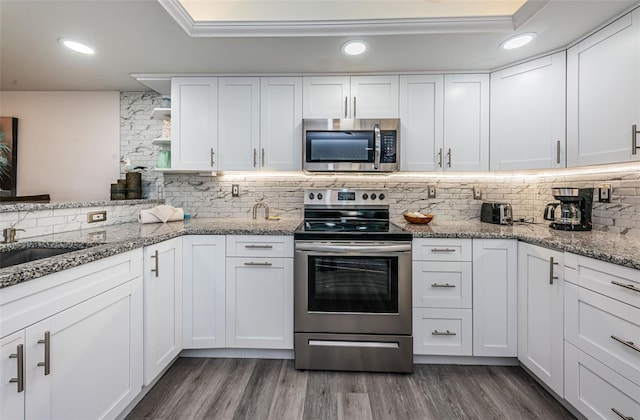 kitchen featuring backsplash, white cabinetry, dark hardwood / wood-style flooring, and appliances with stainless steel finishes