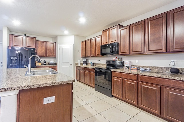 kitchen featuring a center island with sink, light tile patterned floors, black appliances, and sink