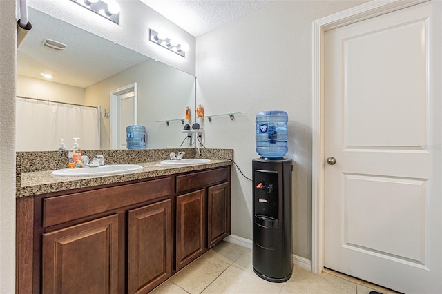 bathroom with vanity, a textured ceiling, and tile patterned floors