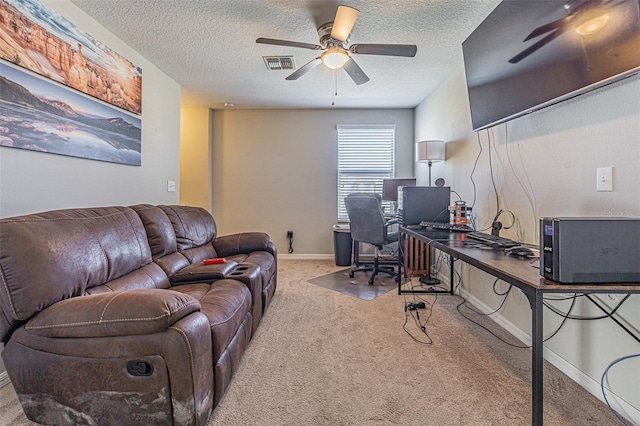 office space with a textured ceiling, ceiling fan, and light carpet