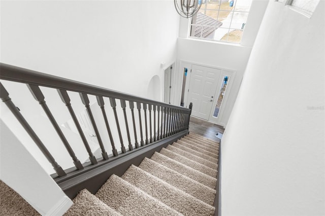 staircase with hardwood / wood-style floors and a towering ceiling