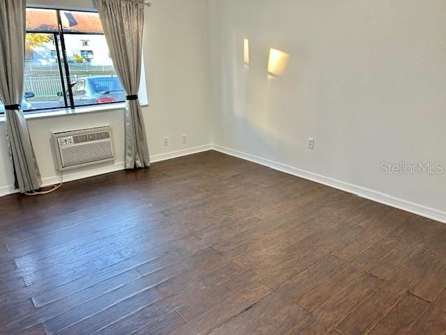 spare room featuring dark hardwood / wood-style flooring and an AC wall unit