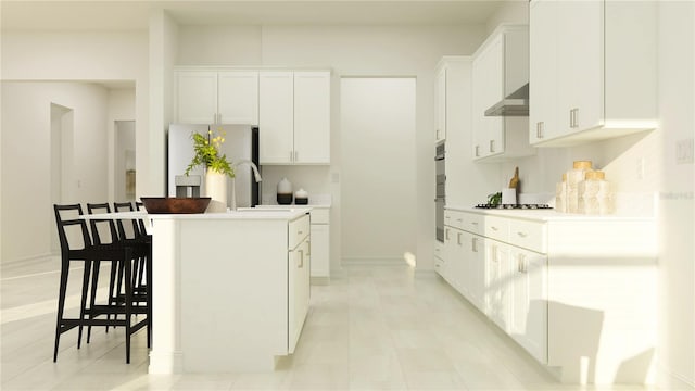 kitchen featuring stainless steel gas stovetop, a center island, white cabinets, wall chimney exhaust hood, and fridge with ice dispenser