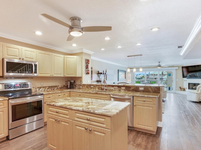 kitchen with hanging light fixtures, stainless steel appliances, kitchen peninsula, crown molding, and a kitchen island