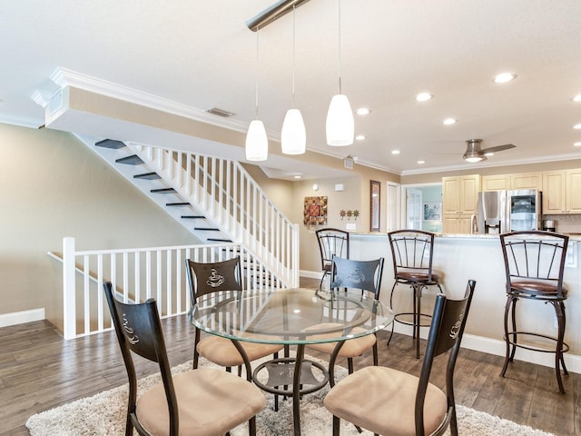 dining space with ceiling fan, ornamental molding, and dark wood-type flooring