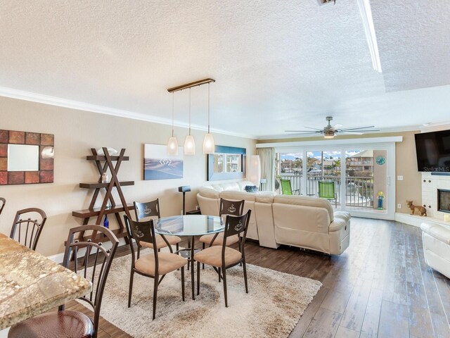 dining room with dark hardwood / wood-style flooring, crown molding, a fireplace, and a textured ceiling