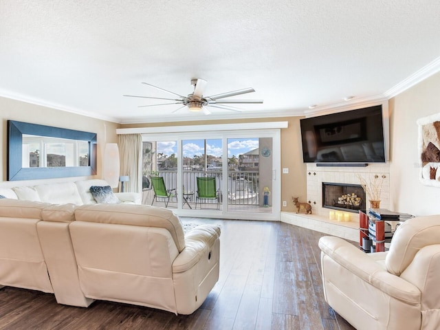 living room featuring ceiling fan, wood-type flooring, ornamental molding, and a textured ceiling