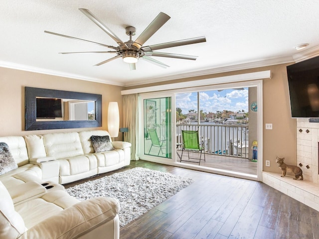 living room featuring hardwood / wood-style flooring, ceiling fan, ornamental molding, and a textured ceiling