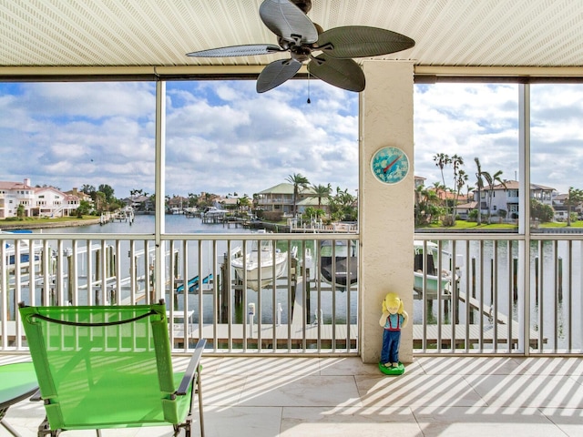 sunroom with ceiling fan and a water view