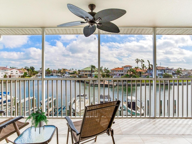 sunroom with ceiling fan and a water view