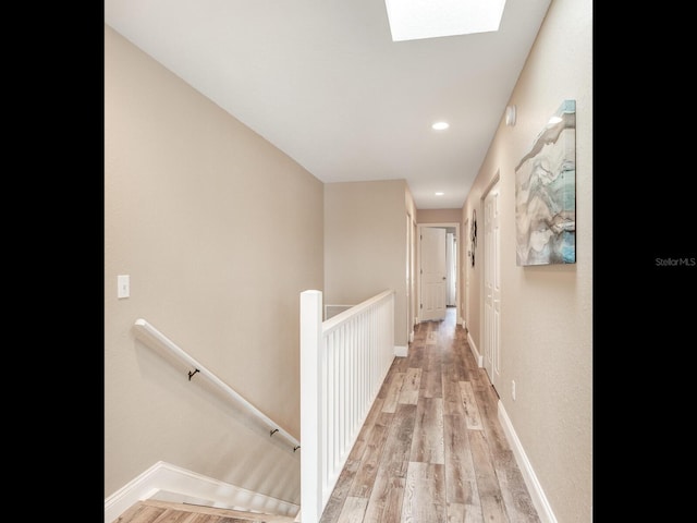 hallway featuring a skylight and light hardwood / wood-style flooring