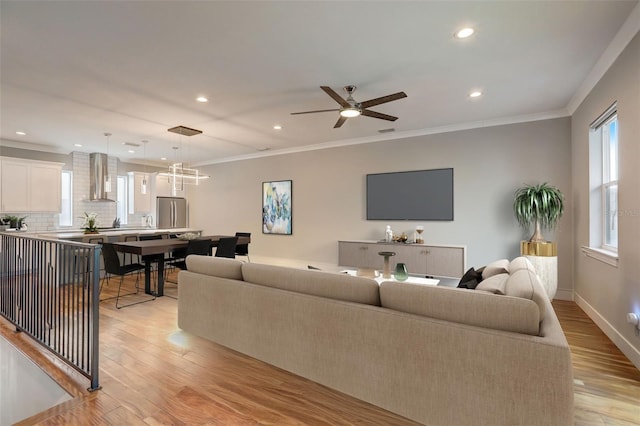 living room with light hardwood / wood-style floors, ceiling fan, and ornamental molding