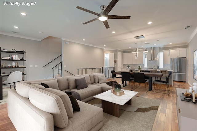 living room featuring ceiling fan, ornamental molding, sink, and light hardwood / wood-style flooring