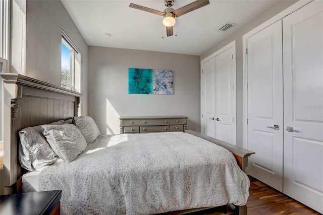 bedroom featuring multiple closets, ceiling fan, and dark hardwood / wood-style floors