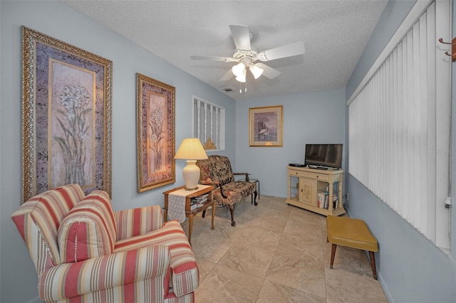 living area with ceiling fan and a textured ceiling